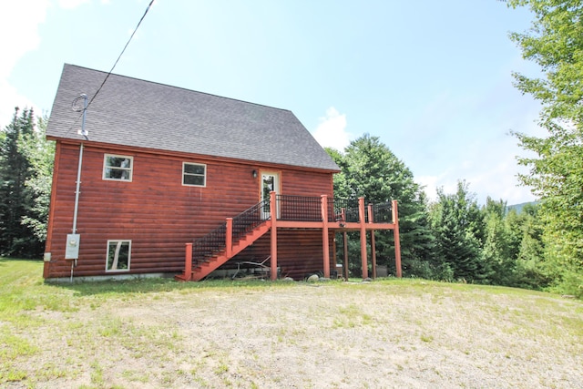 rear view of property featuring a shingled roof, a lawn, stairway, and a wooden deck