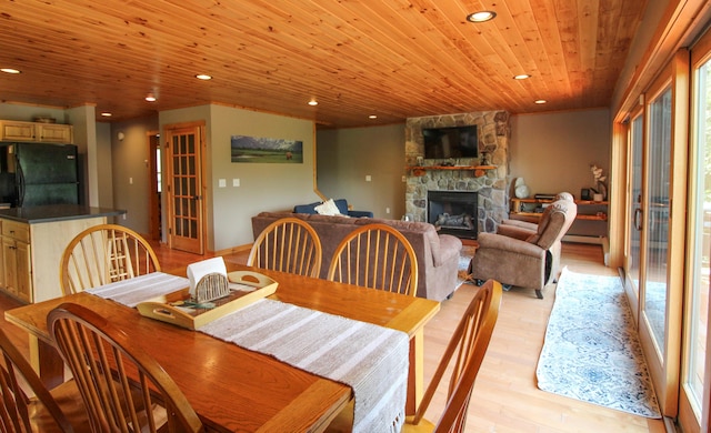 dining space featuring light wood-type flooring, wood ceiling, and a fireplace