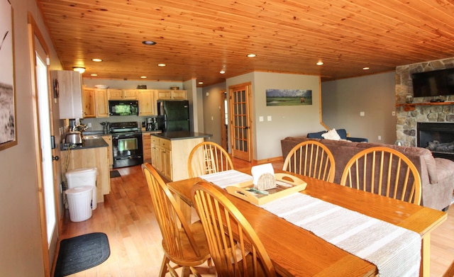 dining area with wooden ceiling, a stone fireplace, light wood-style floors, and recessed lighting