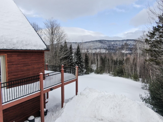 snowy yard featuring a wooded view