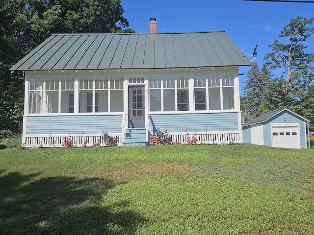 bungalow-style home featuring a chimney, a standing seam roof, metal roof, a detached garage, and a front yard