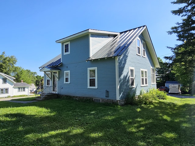 rear view of house featuring metal roof and a yard