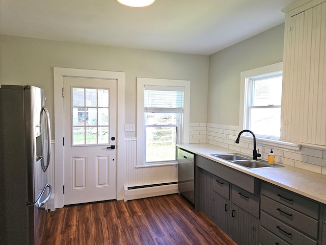 kitchen featuring gray cabinets, a baseboard radiator, stainless steel appliances, a sink, and dark wood-style floors