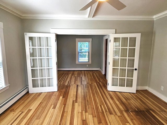 spare room featuring a baseboard radiator, wood finished floors, and crown molding