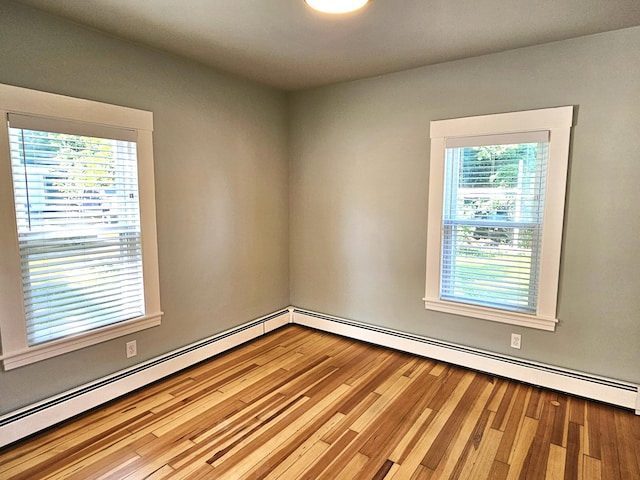 unfurnished room featuring baseboard heating and wood finished floors