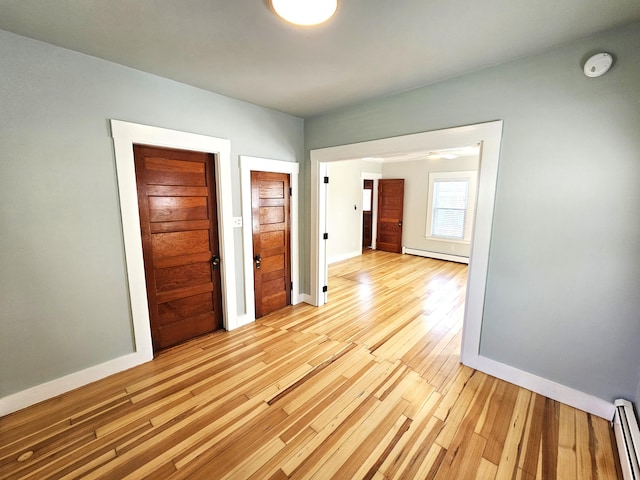 interior space featuring a baseboard radiator, light wood-style flooring, baseboard heating, and baseboards