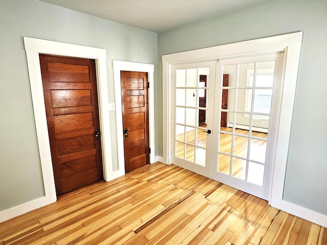 doorway to outside with wood finished floors, french doors, baseboard heating, and baseboards