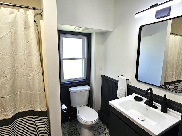 bathroom featuring vanity, toilet, visible vents, and wainscoting