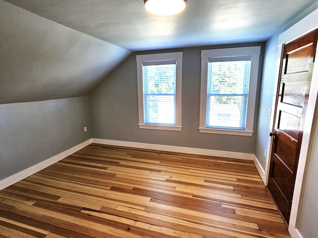 bonus room with hardwood / wood-style floors, lofted ceiling, and baseboards