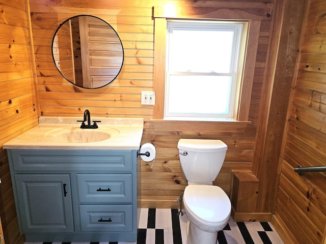bathroom with toilet, wood walls, and vanity