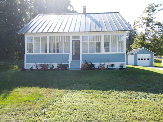 bungalow-style house featuring a standing seam roof, metal roof, an outbuilding, a sunroom, and a garage