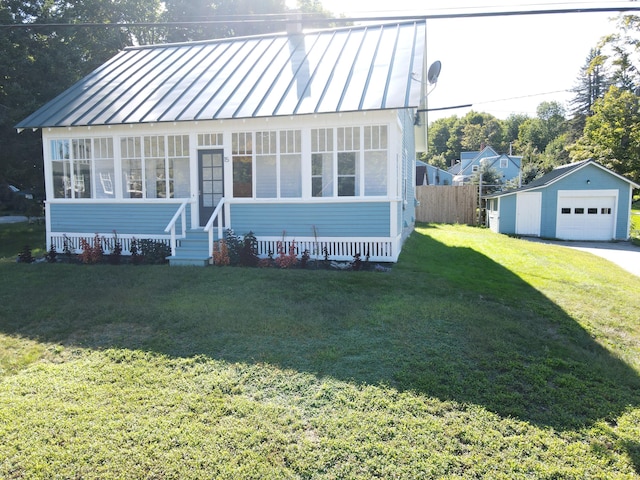 view of front facade featuring a standing seam roof, a front yard, a garage, an outbuilding, and metal roof