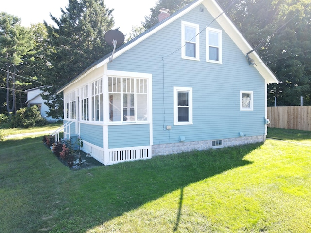 view of home's exterior with a chimney, fence, and a lawn