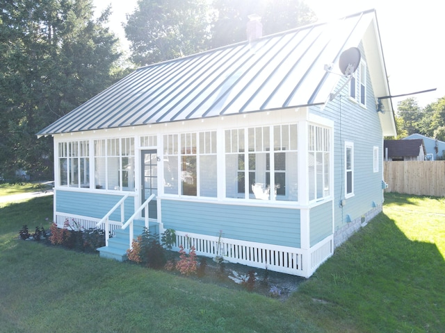view of front of house with a chimney, a standing seam roof, a front yard, and metal roof