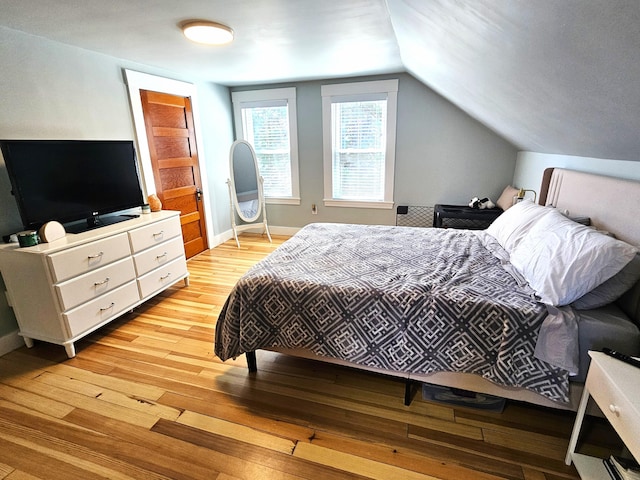 bedroom with baseboards, lofted ceiling, and light wood finished floors