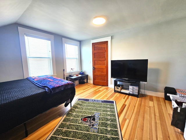 bedroom with lofted ceiling, wood finished floors, and baseboards