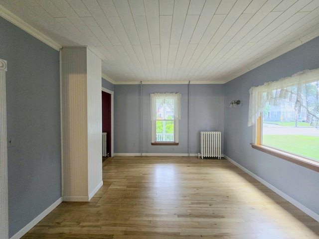 empty room featuring radiator heating unit, light hardwood / wood-style floors, wood ceiling, and ornamental molding