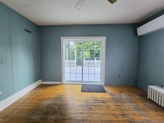 spare room featuring ceiling fan, dark hardwood / wood-style flooring, radiator, a textured ceiling, and an AC wall unit