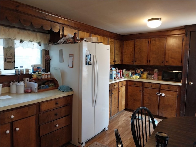 kitchen with backsplash, white refrigerator, and light wood-type flooring