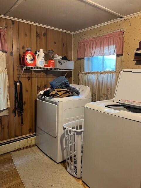 laundry room featuring washing machine and clothes dryer, light hardwood / wood-style floors, crown molding, and wooden walls