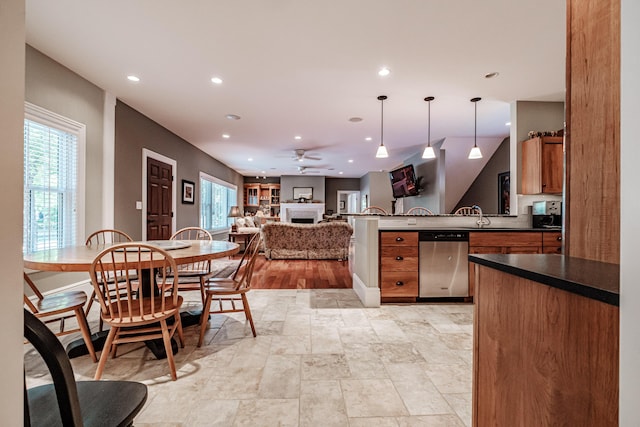 kitchen with stainless steel dishwasher, plenty of natural light, kitchen peninsula, and hanging light fixtures