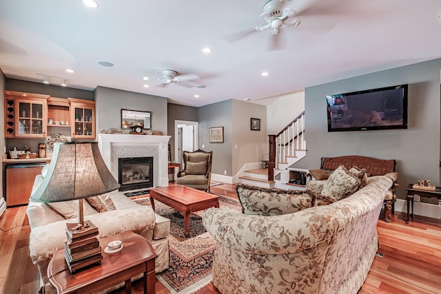 living room featuring ceiling fan, a fireplace, and light hardwood / wood-style flooring