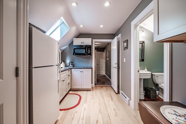 kitchen featuring white cabinetry, light wood-type flooring, lofted ceiling with skylight, and white fridge