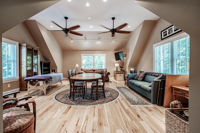 dining room featuring vaulted ceiling, rail lighting, and light wood-type flooring