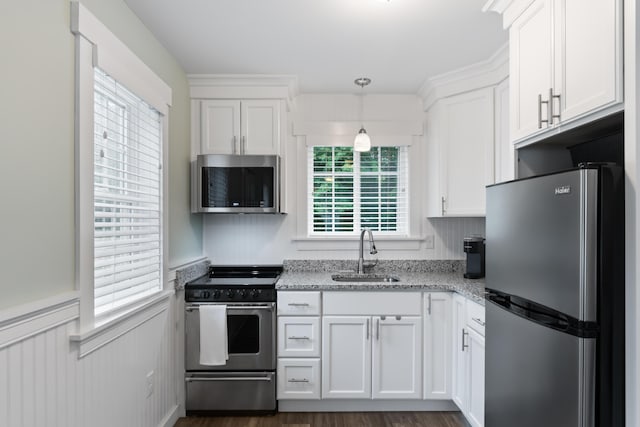 kitchen with pendant lighting, white cabinetry, sink, light stone counters, and stainless steel appliances