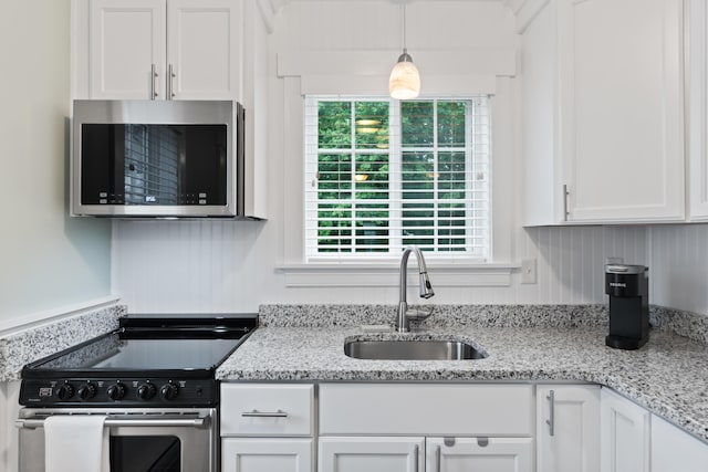 kitchen featuring appliances with stainless steel finishes, sink, pendant lighting, and white cabinets