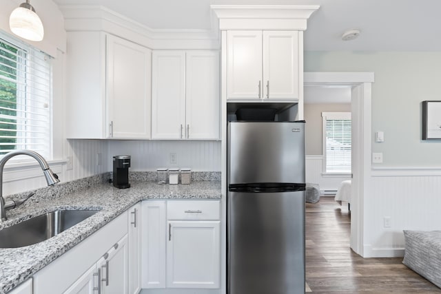 kitchen featuring stainless steel refrigerator, sink, and white cabinets