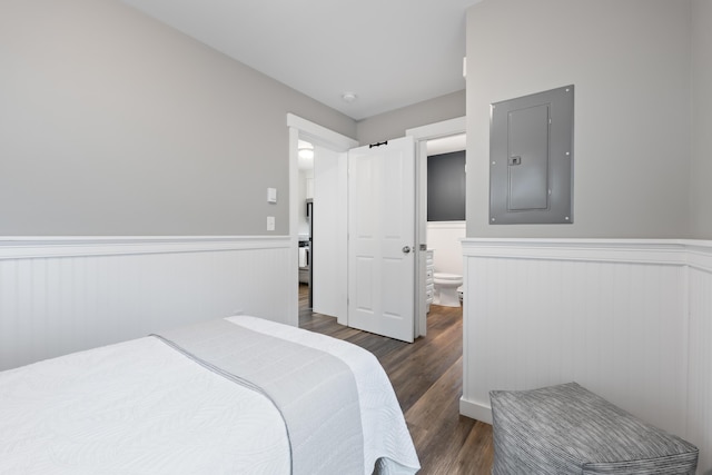 bedroom featuring ensuite bathroom, dark hardwood / wood-style floors, and electric panel