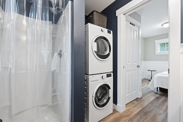 laundry area with stacked washer / drying machine and hardwood / wood-style floors