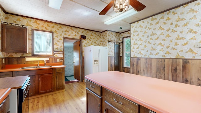 kitchen with crown molding, wood walls, light hardwood / wood-style floors, and white fridge with ice dispenser