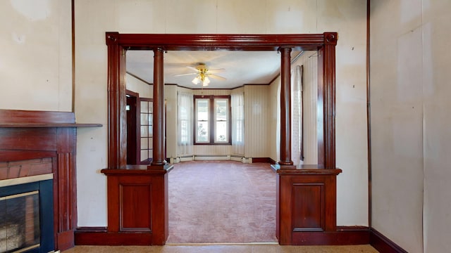 unfurnished living room featuring a baseboard radiator, carpet, ceiling fan, and ornate columns