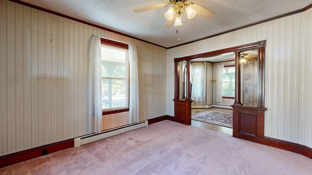 carpeted spare room featuring a baseboard radiator, decorative columns, a healthy amount of sunlight, and a textured ceiling