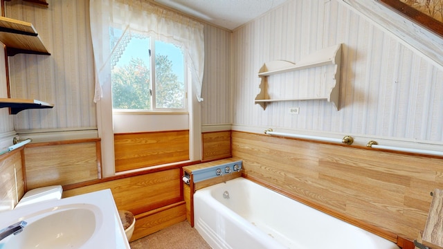 bathroom with a textured ceiling, sink, and a tub