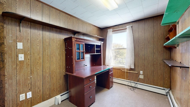 carpeted office featuring wood walls and a baseboard heating unit