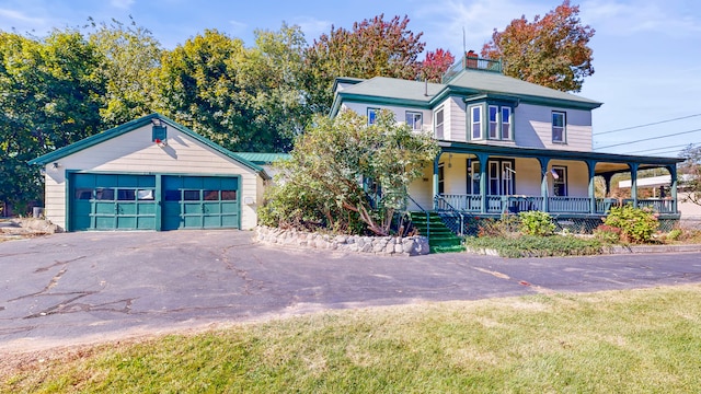 view of front of property with an outbuilding, a porch, a garage, and a front yard