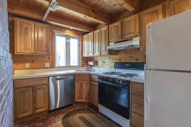 kitchen featuring gas range oven, light countertops, stainless steel dishwasher, freestanding refrigerator, and under cabinet range hood