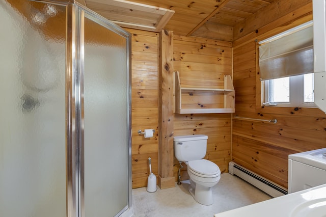 bathroom featuring wooden walls, vanity, baseboard heating, a stall shower, and washer / dryer