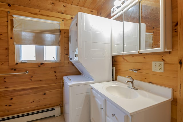 bathroom with wooden walls, a baseboard heating unit, vanity, and stacked washer and clothes dryer