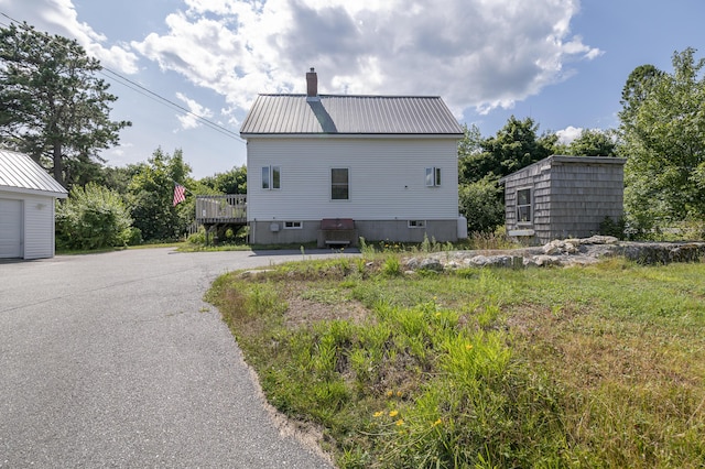 view of side of home with metal roof, a chimney, and a wooden deck