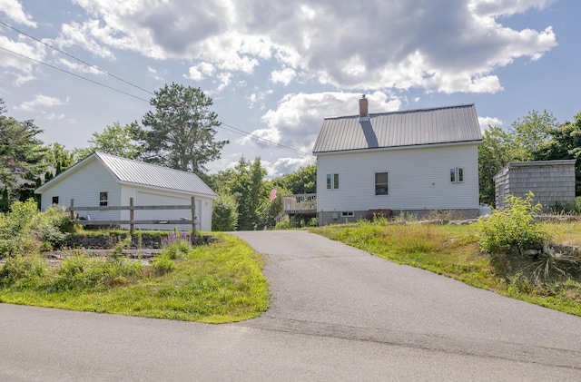 view of side of home with metal roof, a chimney, and an outdoor structure