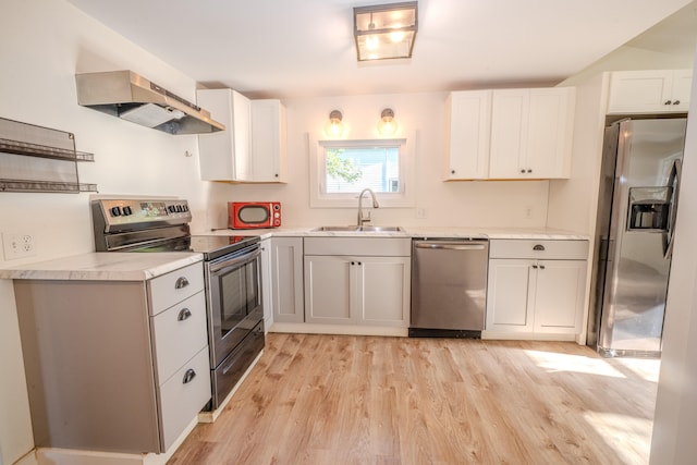 kitchen featuring sink, white cabinetry, stainless steel appliances, extractor fan, and light hardwood / wood-style floors