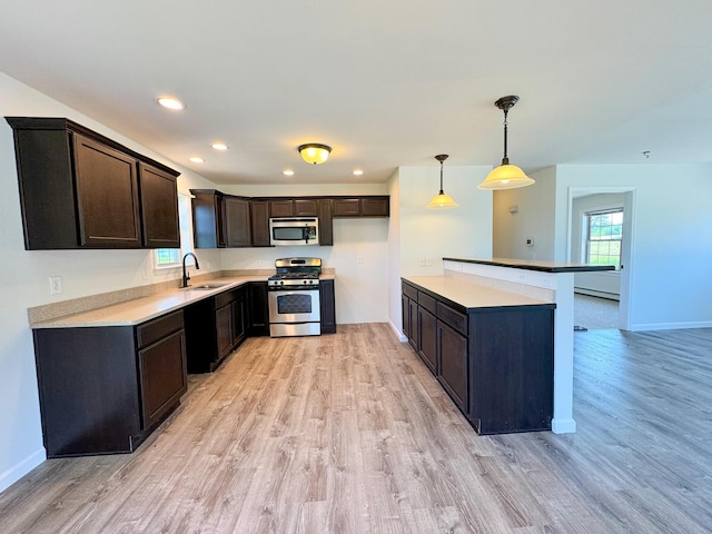 kitchen with recessed lighting, a sink, dark brown cabinets, appliances with stainless steel finishes, and light wood-type flooring