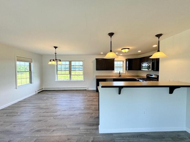 kitchen featuring plenty of natural light, appliances with stainless steel finishes, a kitchen bar, and baseboards