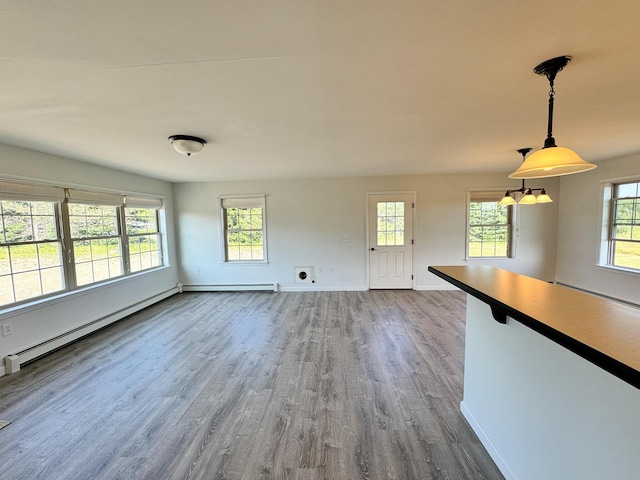 unfurnished living room with wood finished floors, a baseboard heating unit, baseboards, and a baseboard radiator