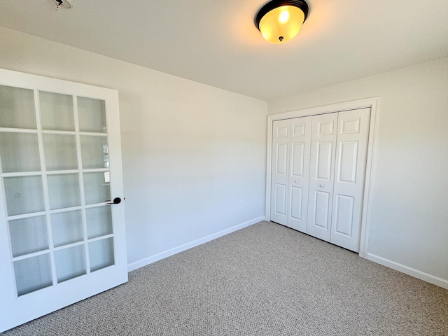 unfurnished bedroom with a closet, baseboards, and carpet flooring