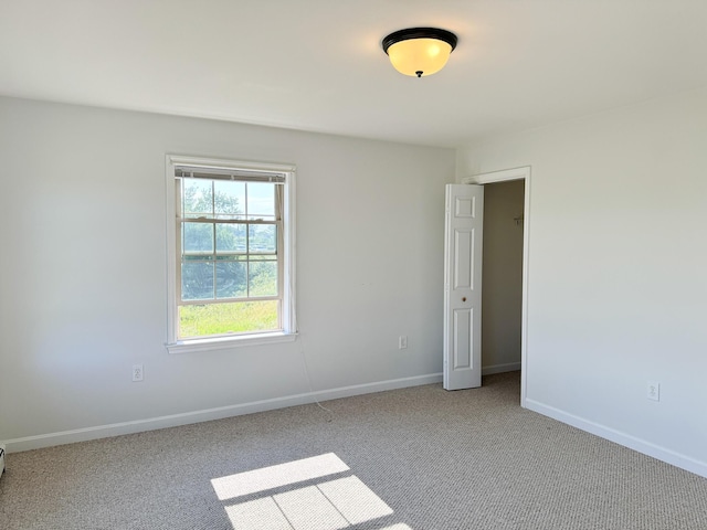 carpeted empty room featuring baseboards